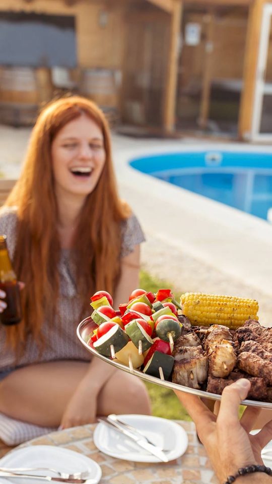 a group of people are having a barbecue at a pool at The Cedars Apartments
