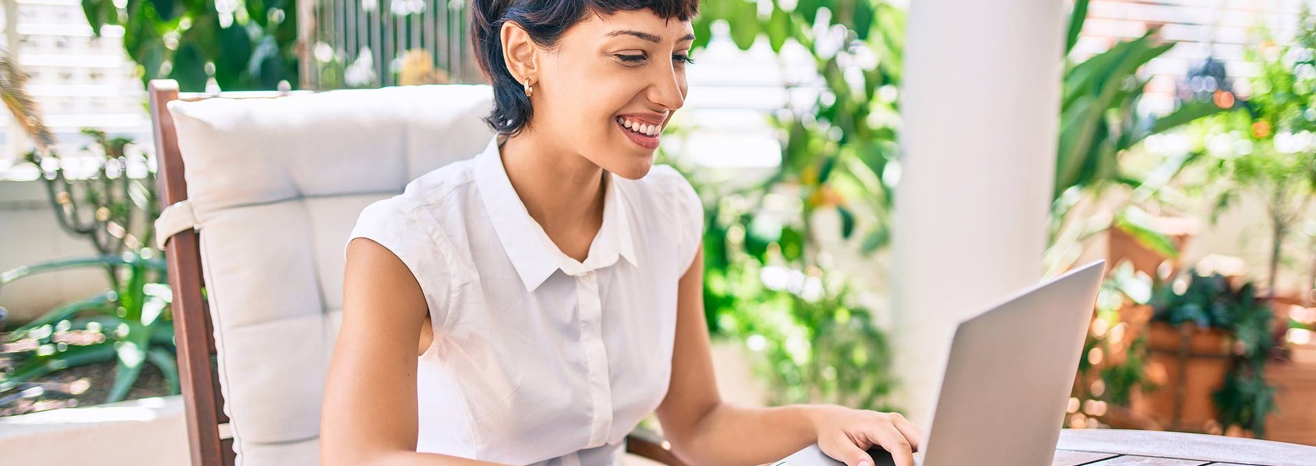 a woman is smiling while using a laptop computer at The Cedars Apartments