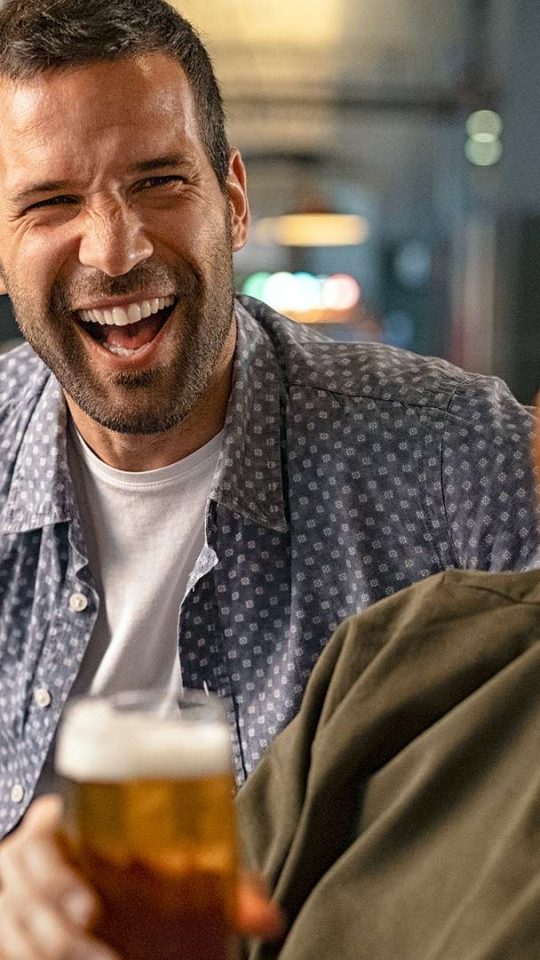 three men laughing and drinking beer at The Cedars Apartments