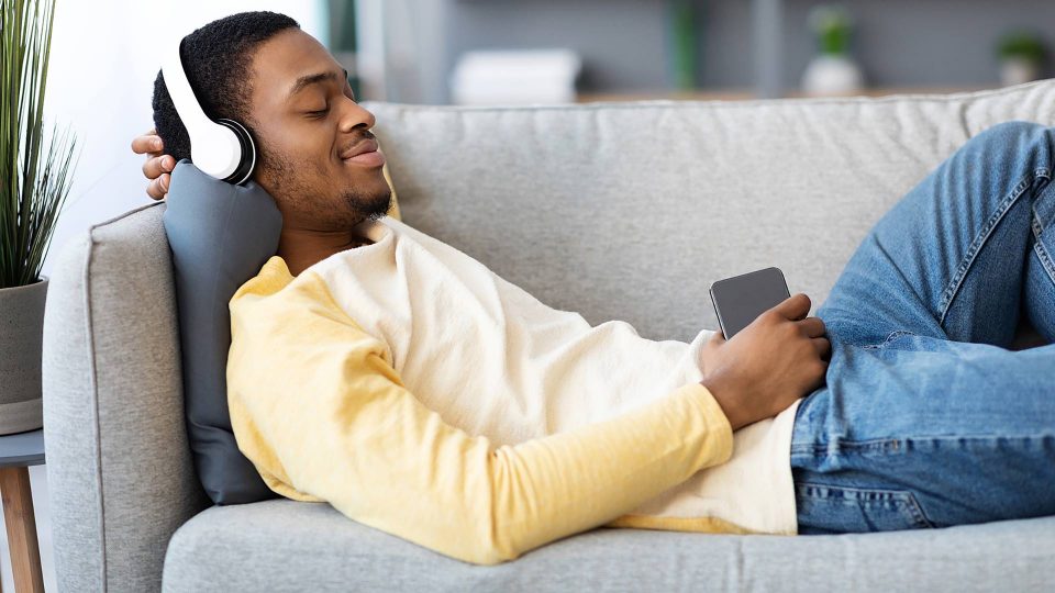a man is laying on a couch listening to music at The Cedars Apartments
